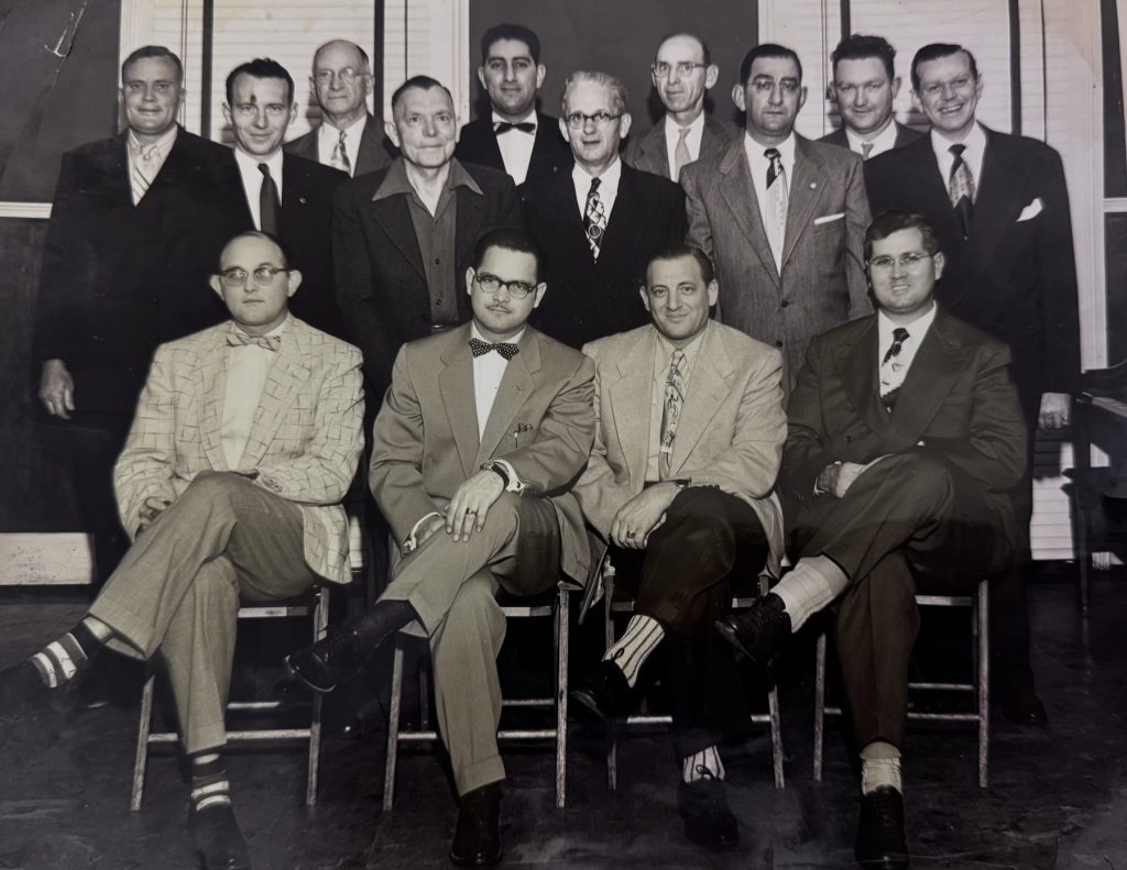 A group portrait from the Flowers family album, men in suits gathered for a dinner