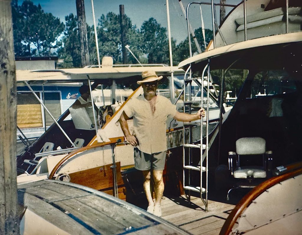 Mack Flowers Sr. in a straw hat, standing on a boat at the marina